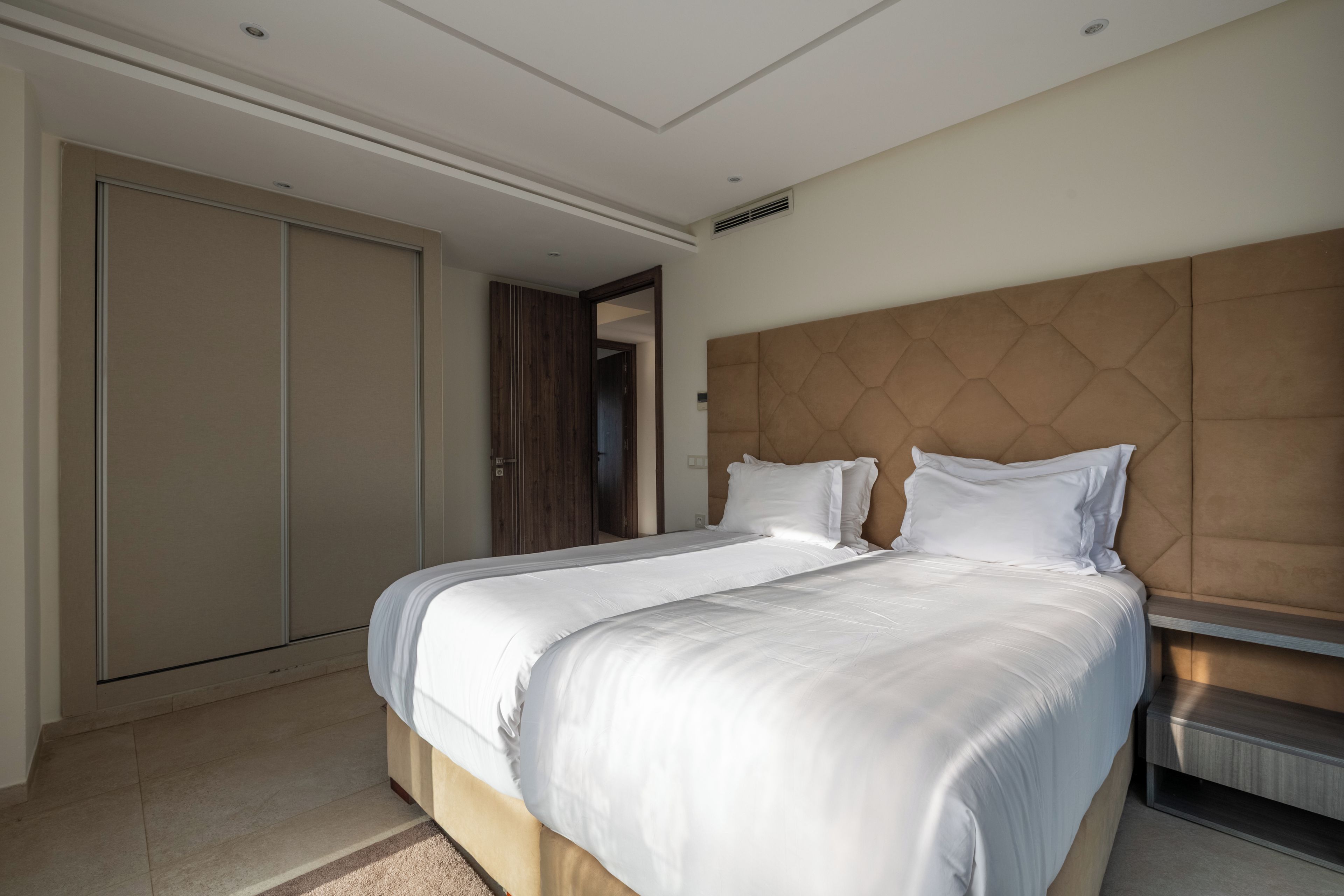 Habitació d'hotel moderna amb un llit gran, un panell de capçal de fusta i un armari.
