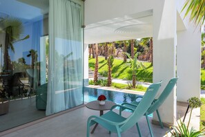 A modern outdoor seating area with a pool view, including a table with a vase of flowers and two chairs. - Le Tanger By Mnar Palm (Al Bahraoyine)