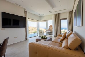 Un salon moderne avec un canapé, un téléviseur à écran plat et une vue sur la plage.