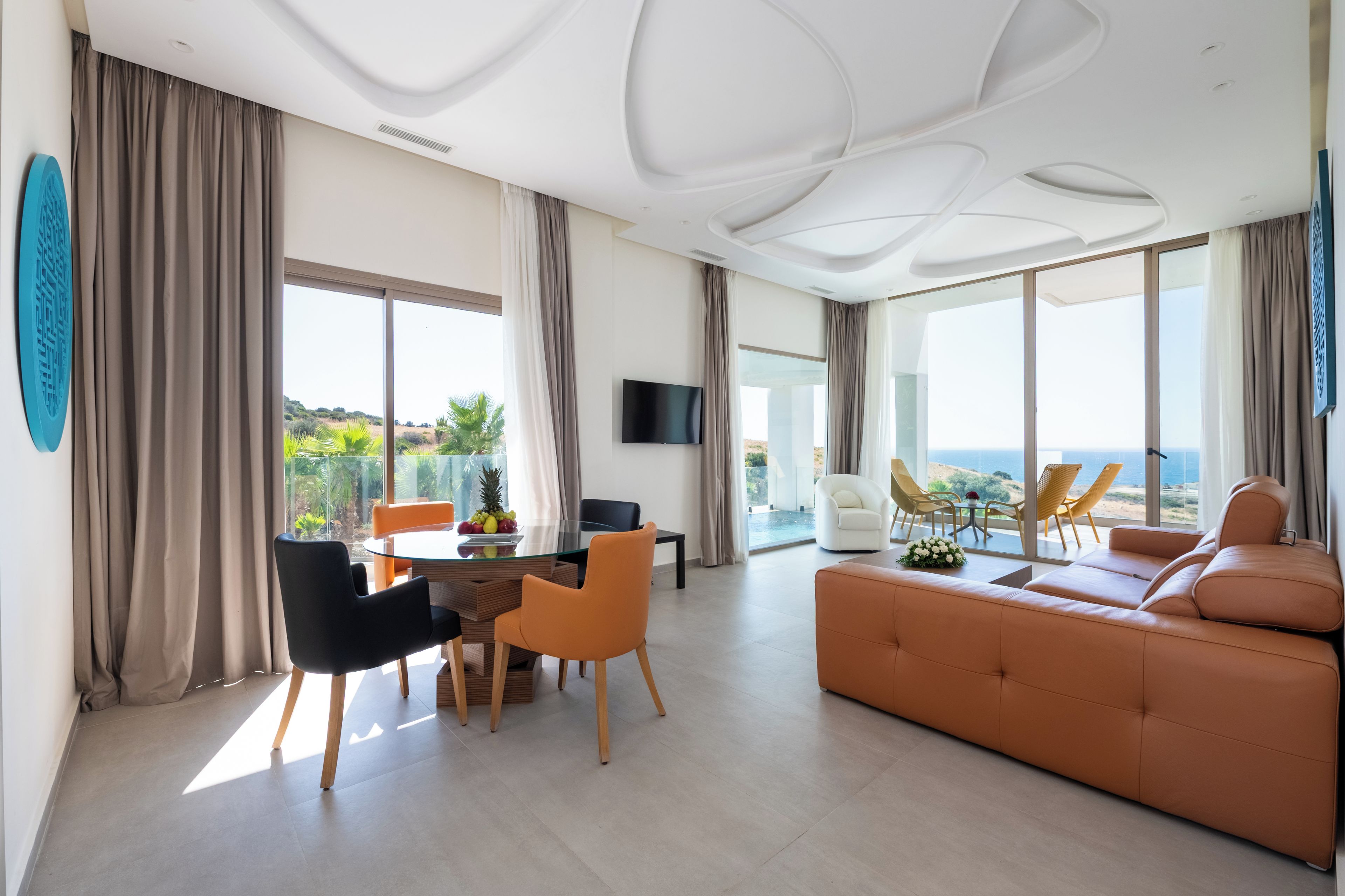 Una sala de estar moderna con sofá, mesa de comedor, sillas y televisor.