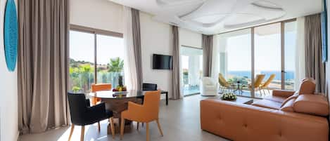 Ein modernes Wohnzimmer mit einer Couch, einem Esstisch, Stühlen und einem Fernseher.