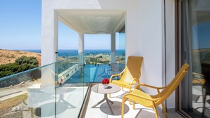 A balcony with glass railings, a table, two yellow chairs, and a vase of flowers. - Le Tanger By Mnar Palm (Al Bahraoyine)