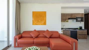 Una sala de estar moderna con un sofá seccional, una mesa de centro con flores y una cocina al fondo.