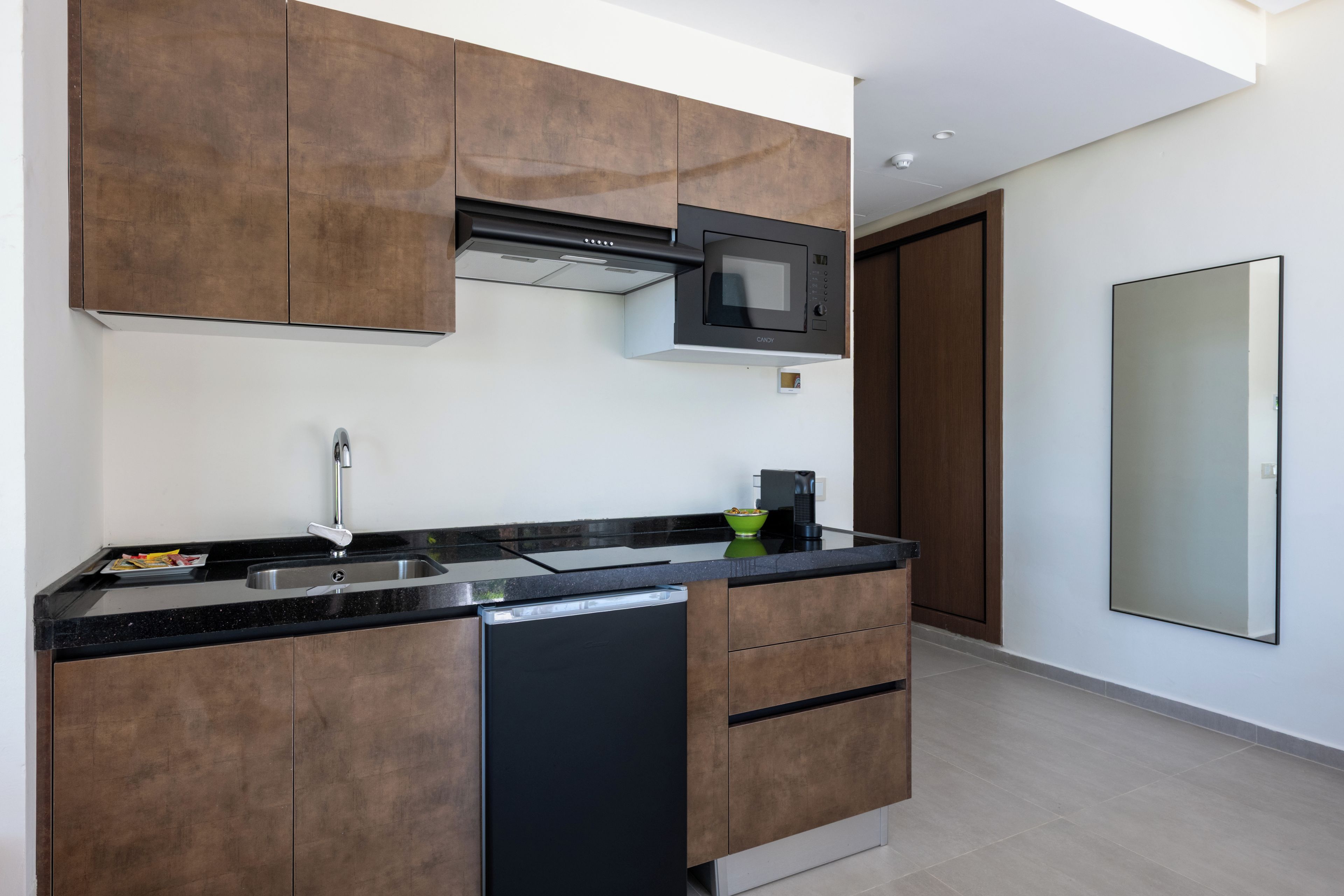 Una cocina moderna con armarios de madera oscura, un microondas integrado y un lavavajillas.