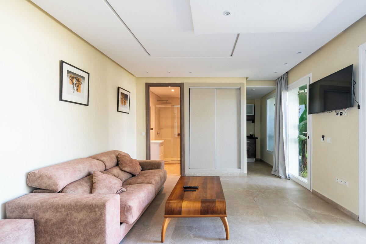A modern living room with a sofa, a wooden coffee table, and a TV mounted on the wall.