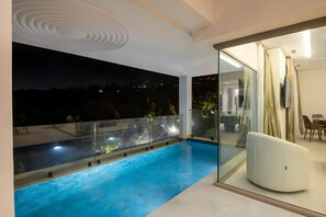 A modern balcony with a swimming pool, glass railings, and a view of the night sky. - Le Tanger By Mnar Palm (Al Bahraoyine)