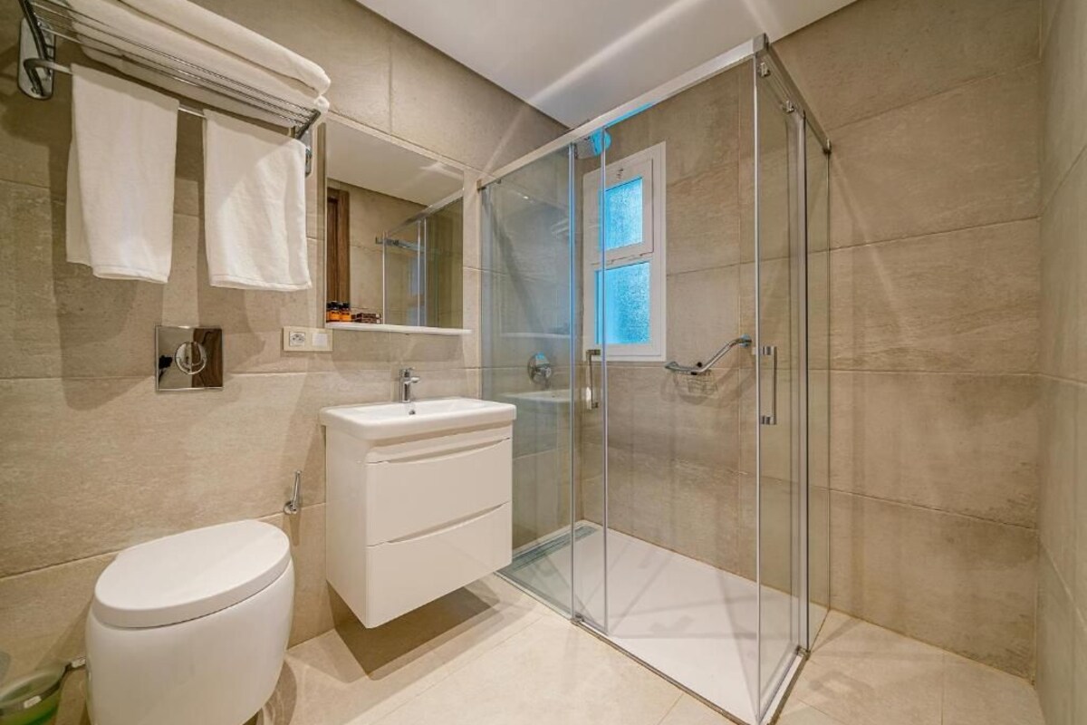 Een moderne badkamer met een douchecabine van glas, een wit toilet en een wastafel met spiegel.