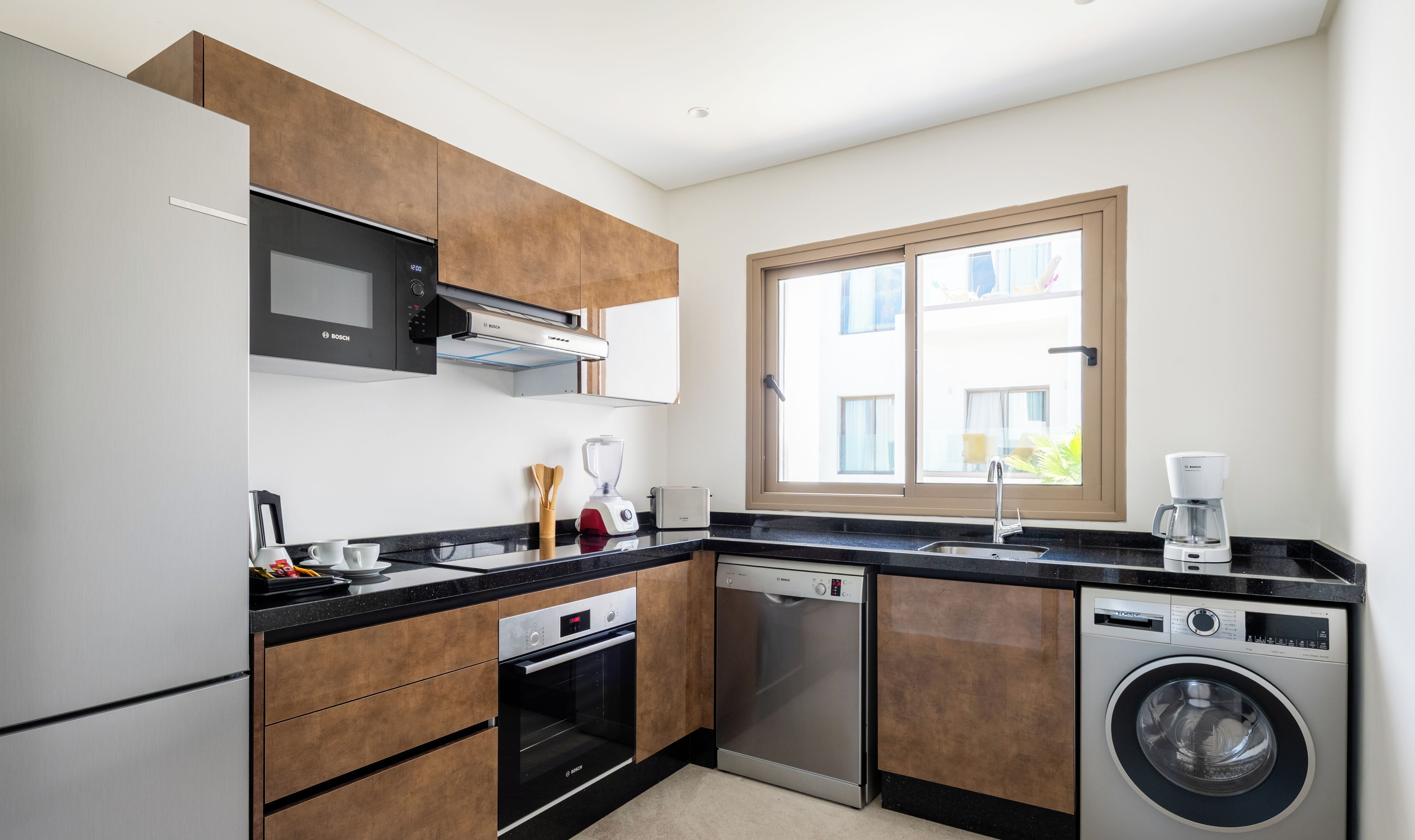 Een moderne keuken met Bosch apparatuur, waaronder een magnetron, oven, vaatwasser en wasmachine.