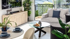 Un salon moderne avec une table basse en verre, un canapé et un coin repas comprenant des chaises et une table mise pour un repas.