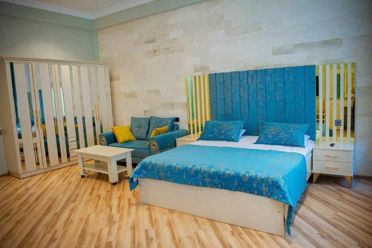 A bedroom with a large bed, a sofa, a nightstand, and a wardrobe.
