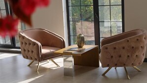Un salon moderne avec deux fauteuils à capitonnage, une table basse en bois et un vase.