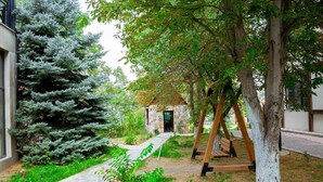 Un bâtiment en pierre avec une façade en pierre, une balançoire en bois et un chemin menant à une entrée en pierre.