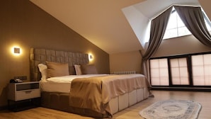 Une chambre à coucher avec un grand lit, une table de chevet, une commode, une fenêtre avec des rideaux et un puits de lumière.