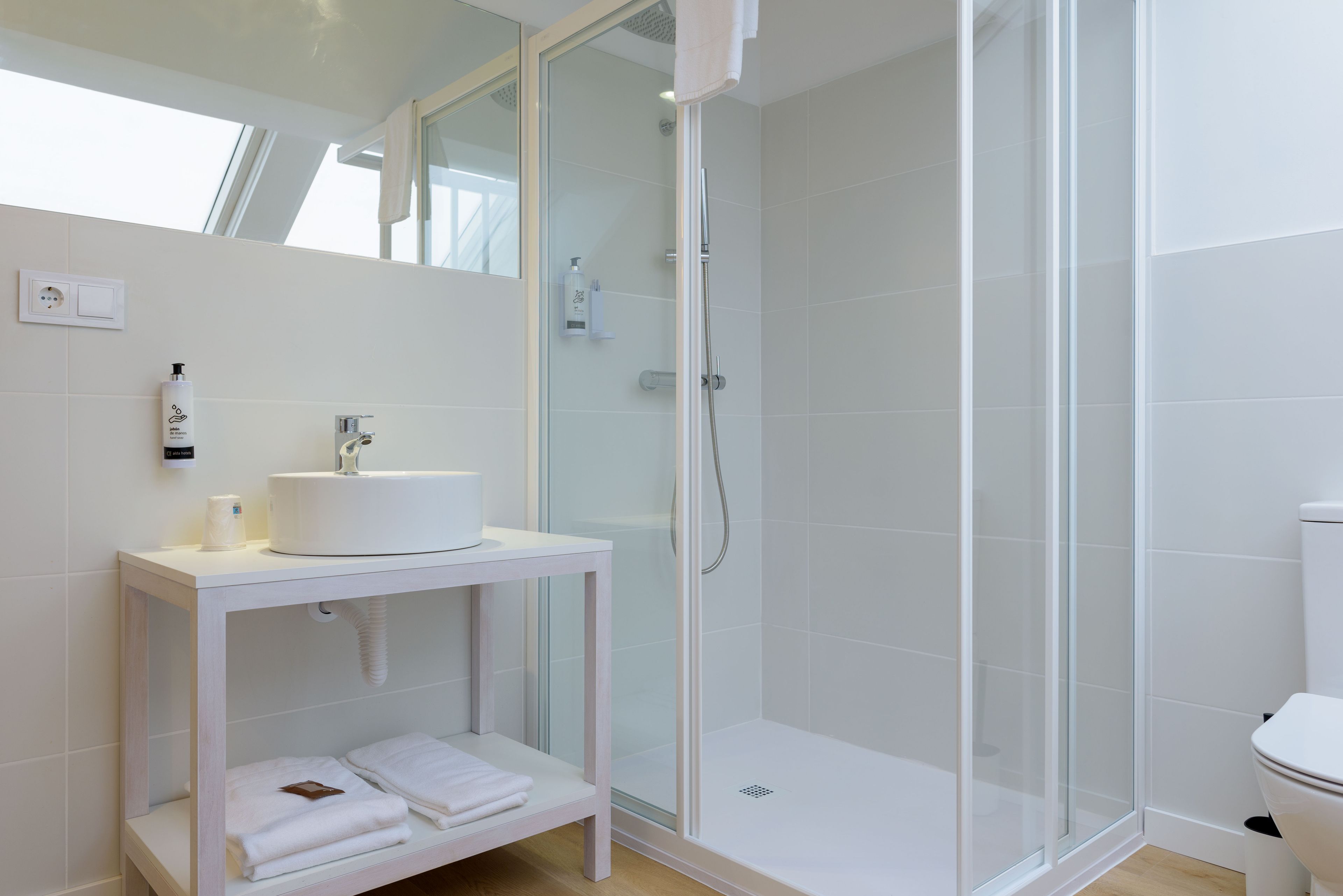 A modern bathroom with a glass-enclosed shower, a white sink, and a towel rack.