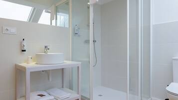 A modern bathroom with a glass-enclosed shower, a white sink, and a towel rack.