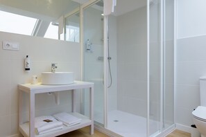 A modern bathroom with a glass-enclosed shower, a white sink, and a towel rack. - Alda Corrubedo (Ribeira)