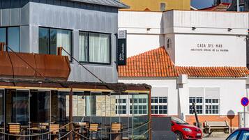 Un edificio con un letrero que dice 'Casa del Mar' y un coche rojo estacionado adelante.