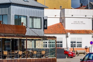 Un edificio con un letrero que dice 'Casa del Mar' y un coche rojo estacionado adelante.