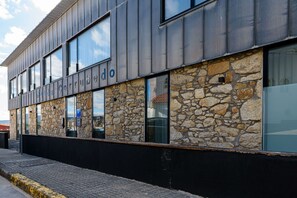 A modern building with a stone facade and large windows. - Alda Corrubedo (Ribeira)