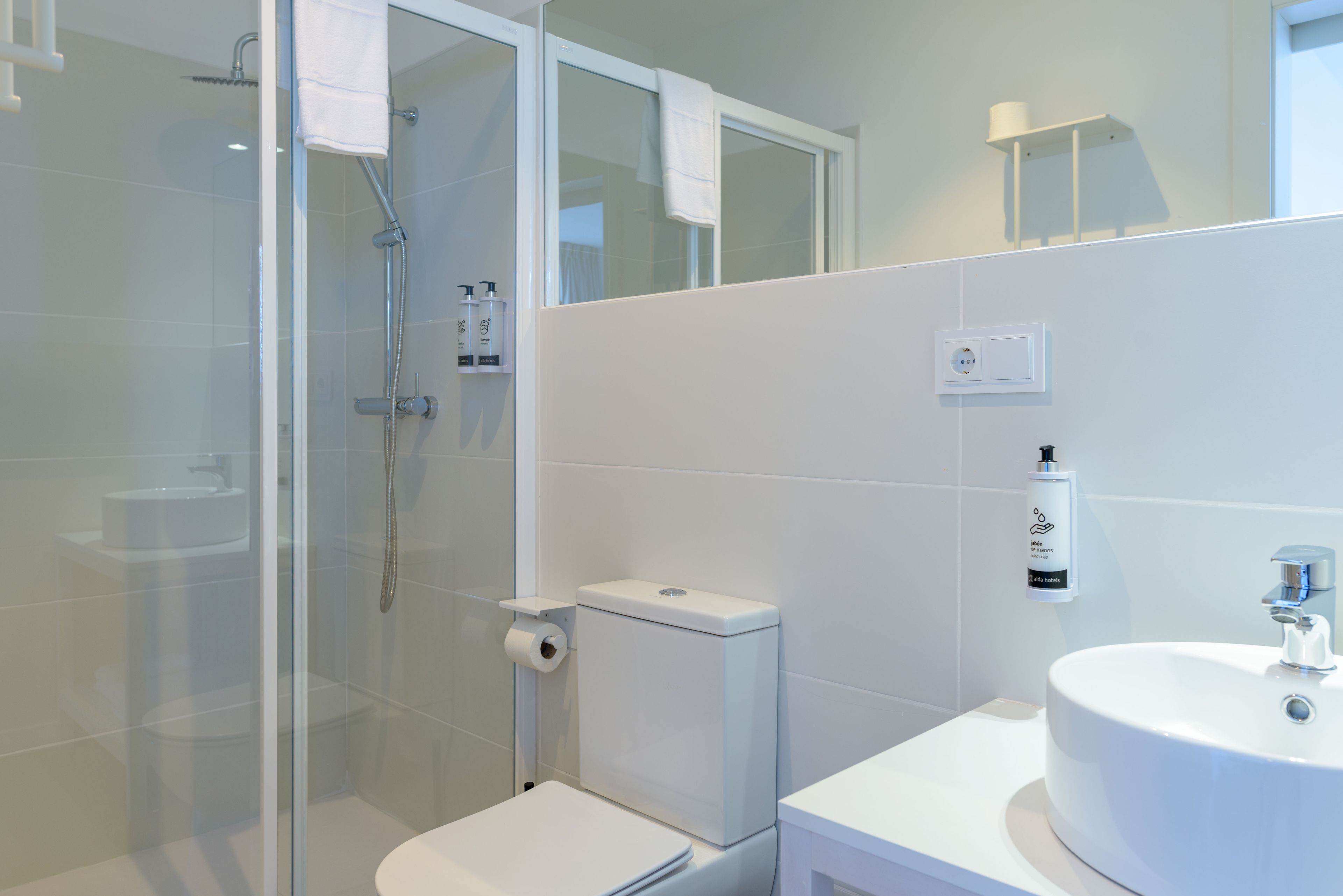 A modern bathroom with a glass-enclosed shower, a toilet, and a sink.