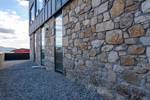A stone building with large windows and a gravel ground. - Alda Corrubedo (Ribeira)