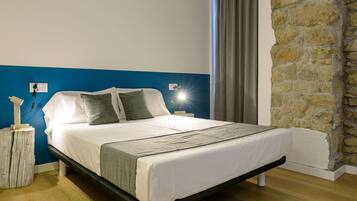 A bed with white bedding, a stone wall, and a blue accent wall.