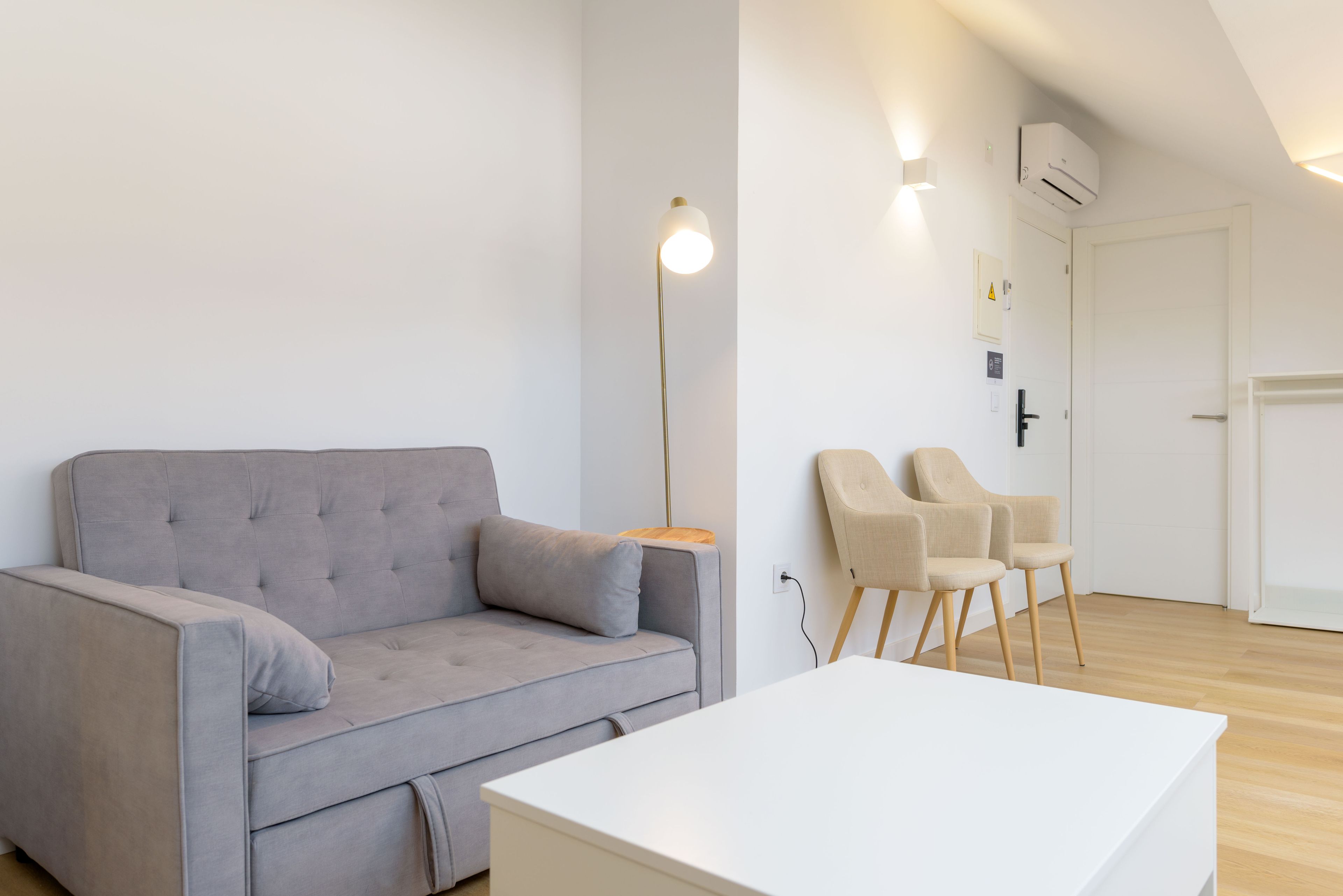 A modern living room with a grey sofa, a white coffee table, and two beige chairs.