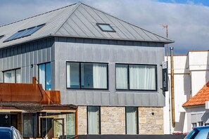 A modern two-story building with large windows and a sloped roof. - Alda Corrubedo (Ribeira)