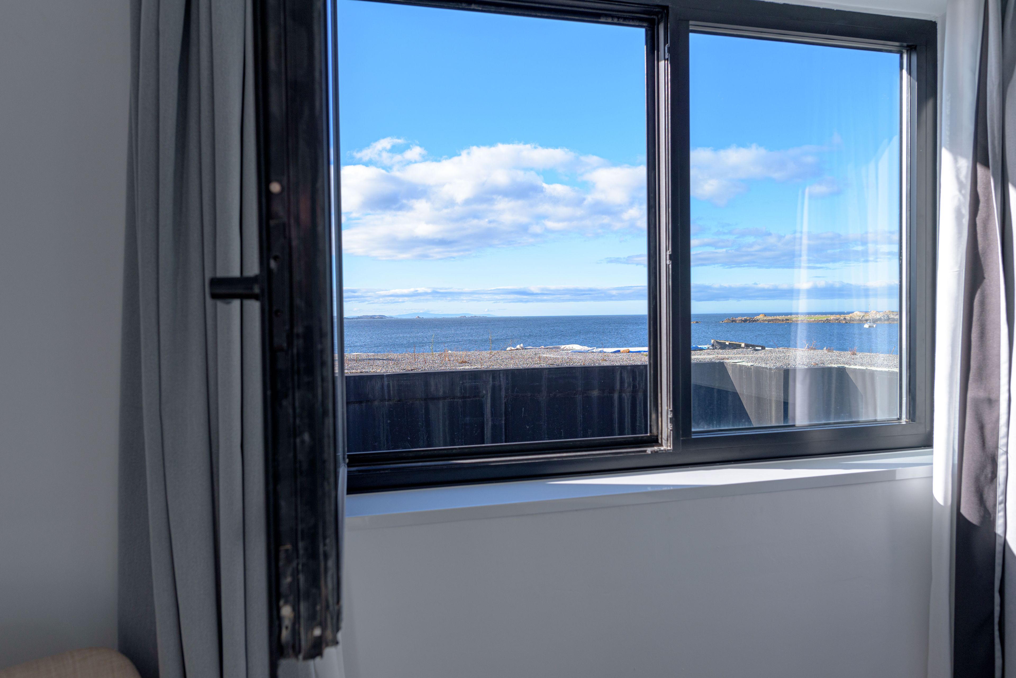 A room with a large window overlooking a coastal area.