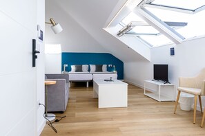 A modern living room with a skylight, a grey sofa, a white coffee table, and a television on a stand. - Alda Corrubedo (Ribeira)
