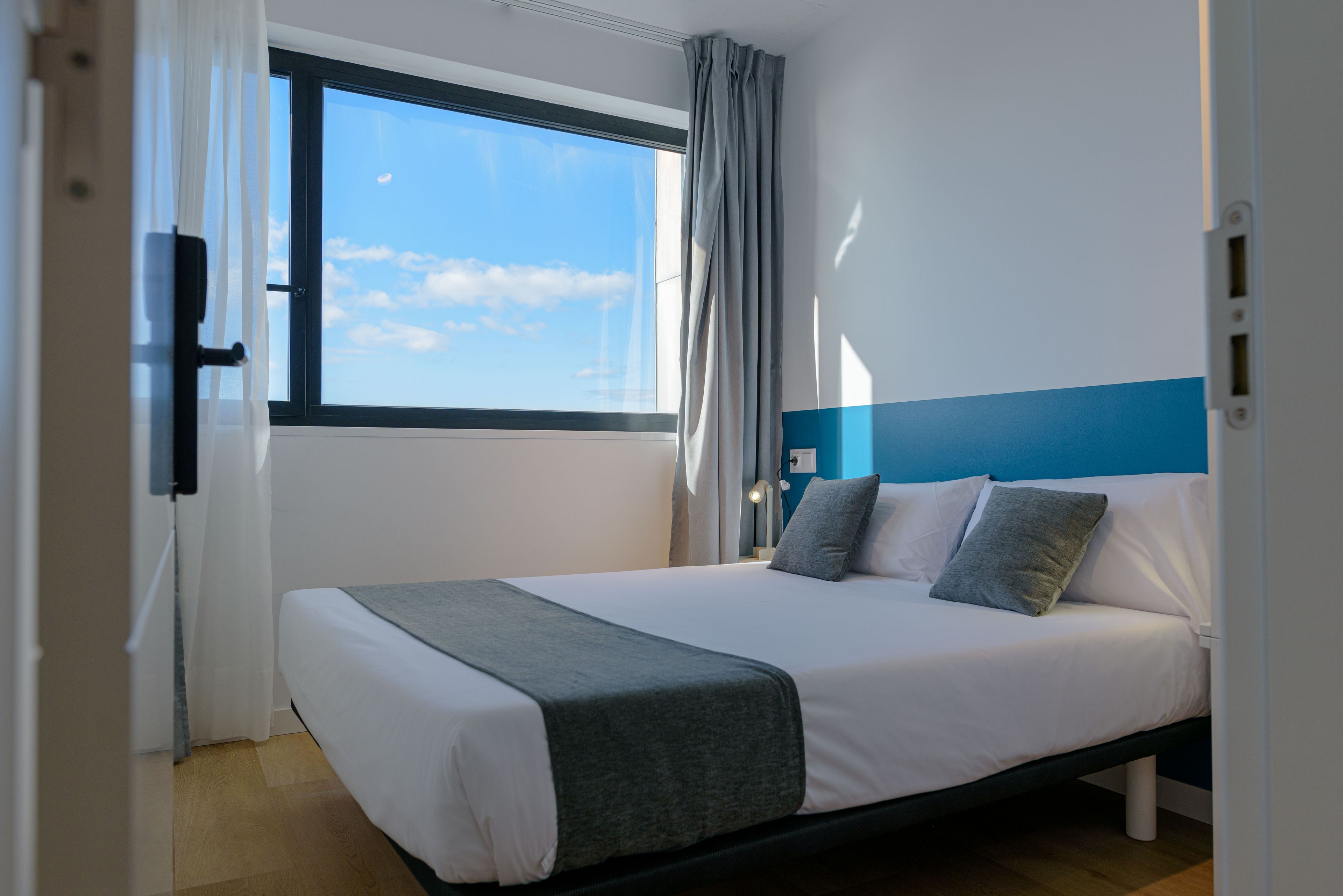 Un dormitorio con cama, ventana y vista al cielo.