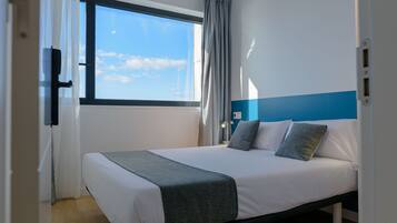 Un dormitorio con cama, ventana y vista al cielo.