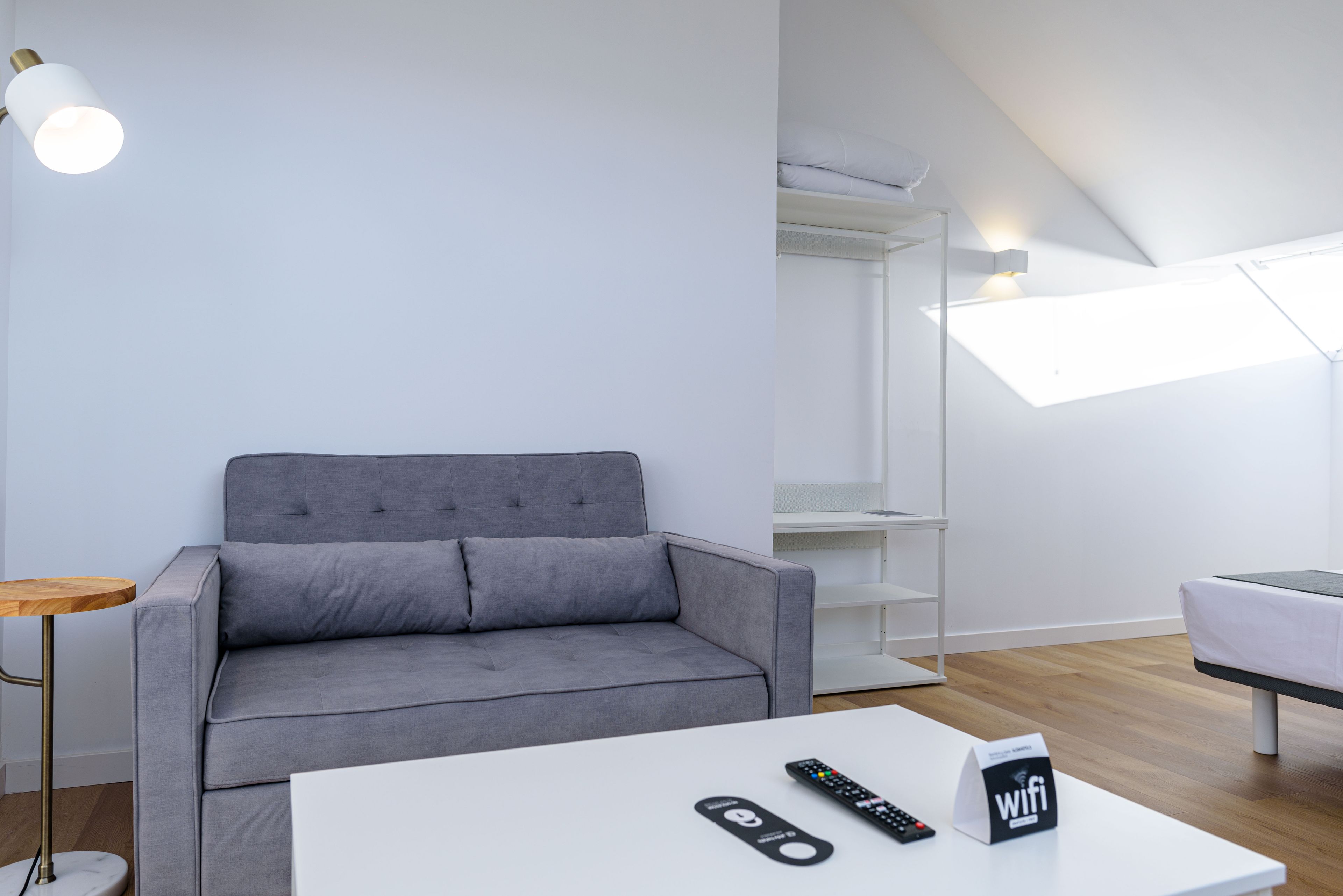 A modern living room with a grey sofa, a white coffee table, a remote control, and a WiFi sign.