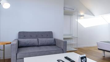 A modern living room with a grey sofa, a white coffee table, a remote control, and a WiFi sign.