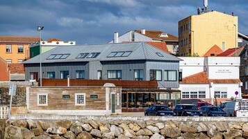 Un bâtiment moderne doté d’un toit plat, de grandes fenêtres et d’un mur en pierre en premier plan.