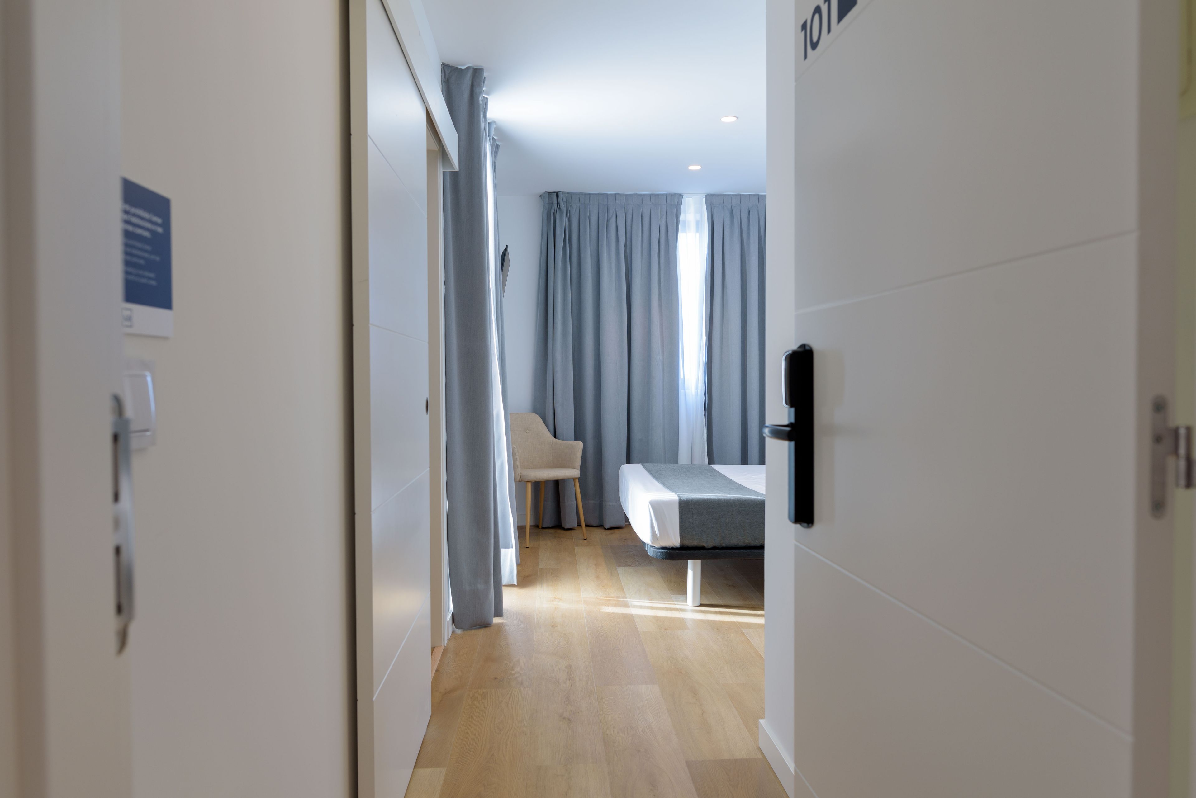 Una habitación de hotel moderna con una cama, una silla y un escritorio.