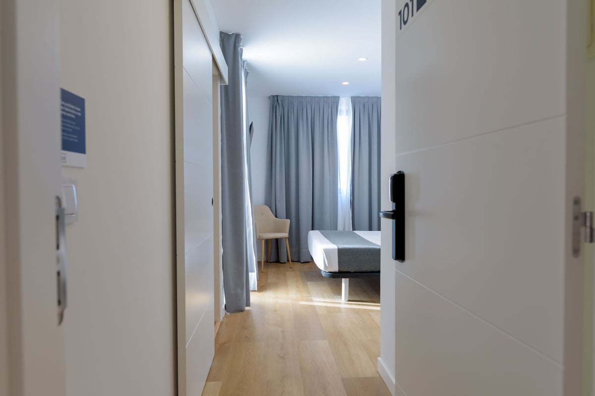 A modern hotel room with a bed, a chair, and a desk.