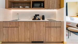 Une cuisine moderne avec des meubles en bois, un four à micro-ondes encastré et un plan de travail sur lequel se trouvent une machine à café et des verres.