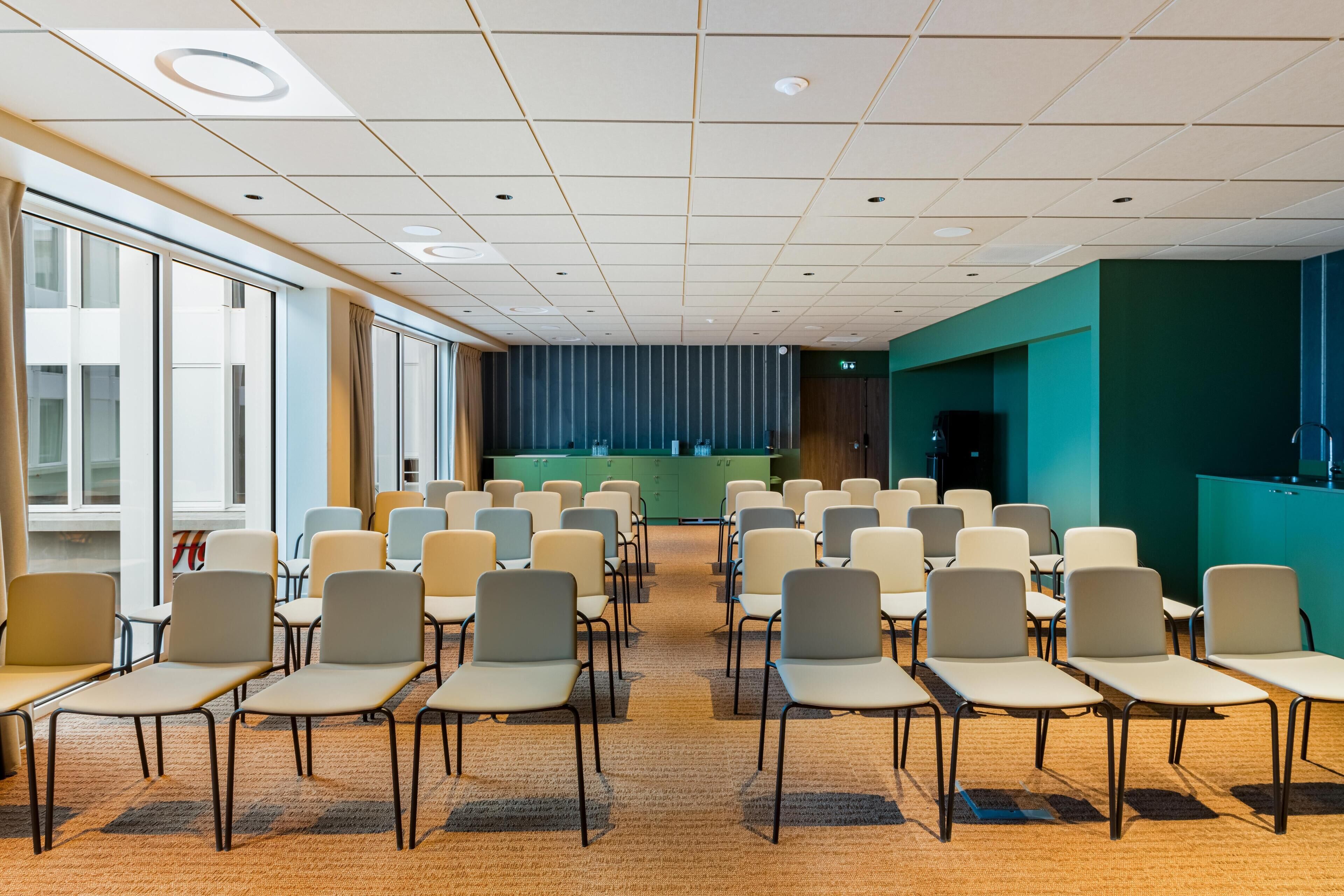 A conference room with rows of chairs, a stage, and a reception desk.