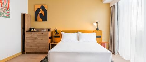 Una camera d'albergo con un letto, un comodino, una lampada, un guardaroba in legno e un quadro appeso al muro.