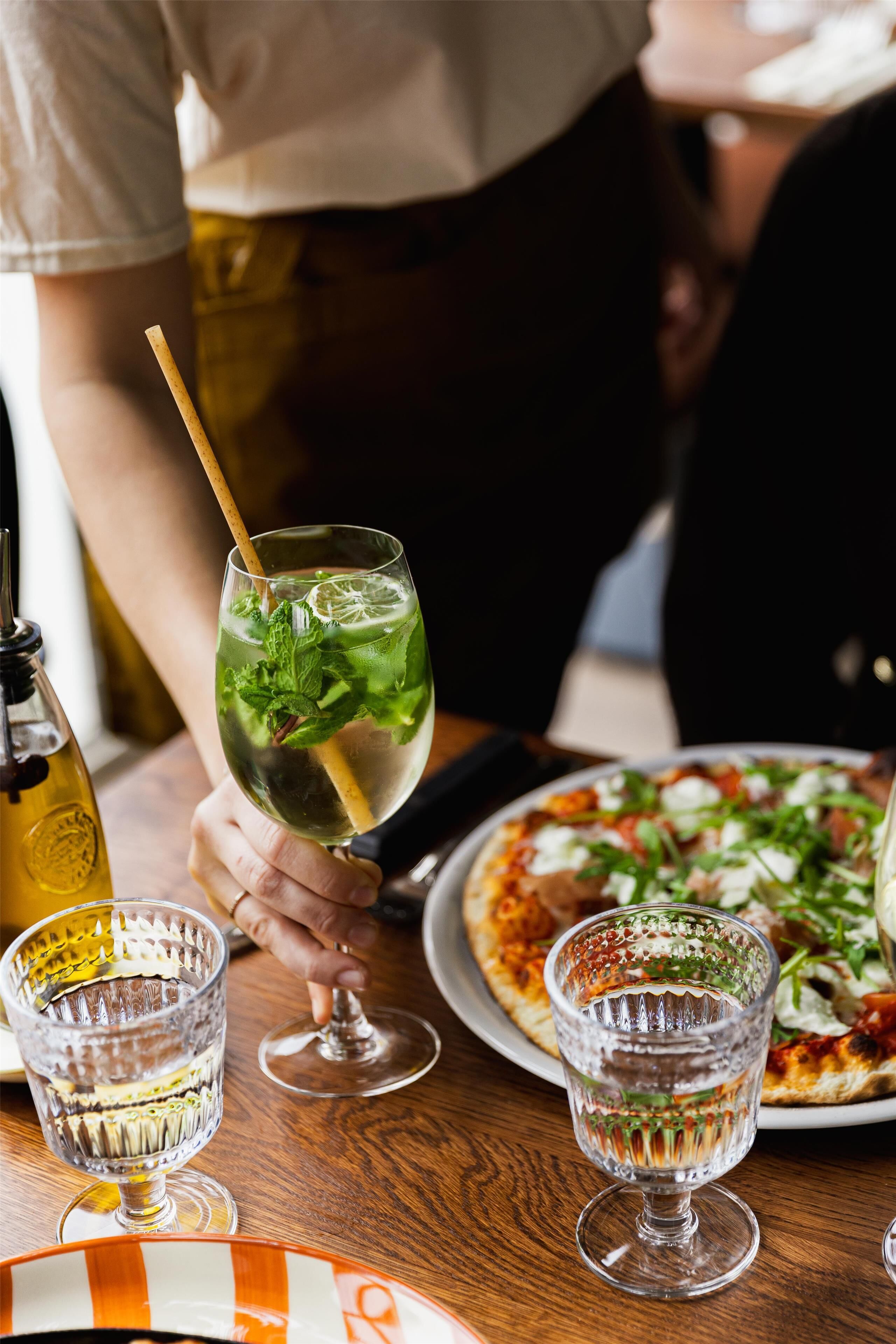 A dining table with a glass of water, a bottle, and a plate of food.