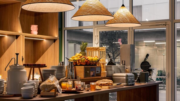 Un comptoir de petit-déjeuner proposant une variété d’aliments, un panier de fruits et une machine à café.