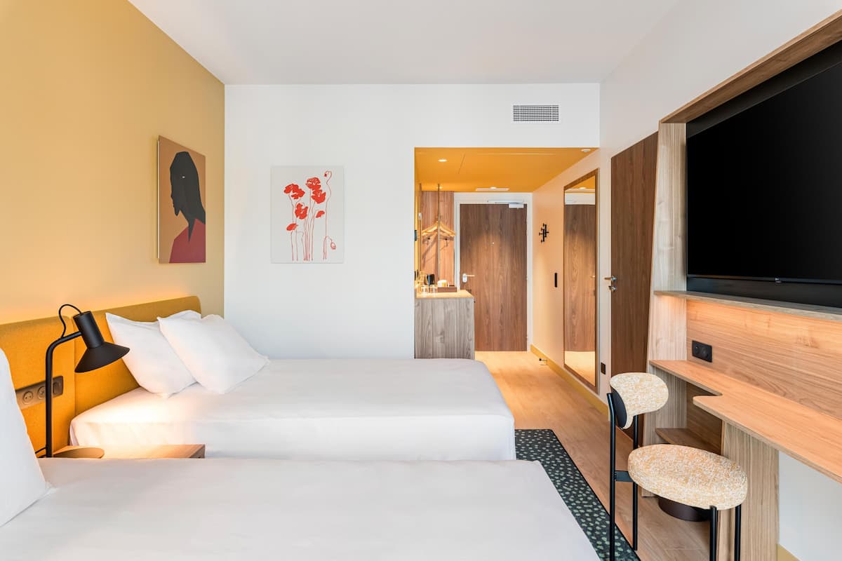Een moderne hotelkamer met een bed, een bureau, een televisie en kunstwerken aan de muur.