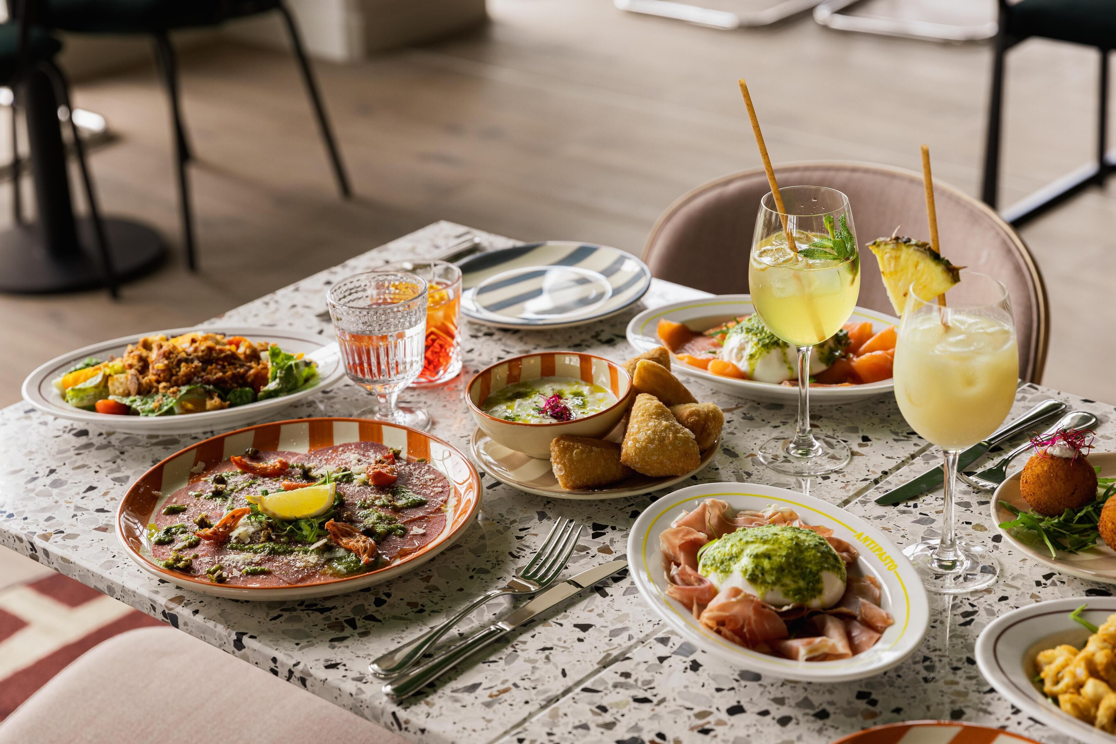 Una mesa de comedor con diversos platos y bebidas, sugiriendo un ambiente de restaurante.