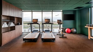Une salle de sport équipée de tapis de course, de ballons d’exercice et d’une grande fenêtre donnant sur l’extérieur.