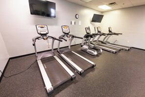 A fitness area with treadmills, a TV mounted on the wall, and a clock. - Hope Hotel & Conference Center (Dayton)
