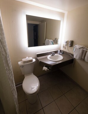 A bathroom with a toilet, sink, and mirror. - Hope Hotel & Conference Center (Dayton)