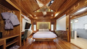 A spacious bedroom with a large bed, wooden walls, a TV, and a bathroom visible through an open door. - Calisto Valley I Luxury Pool Villa Krabi (Krabi)