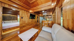 A wooden interior with a bed, sofa, dining area, and TV. - Calisto Valley I Luxury Pool Villa Krabi (Krabi)