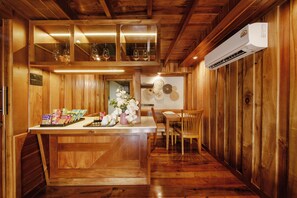 A wooden interior with a kitchen counter, dining area, and an air conditioning unit. - Calisto Valley I Luxury Pool Villa Krabi (Krabi)